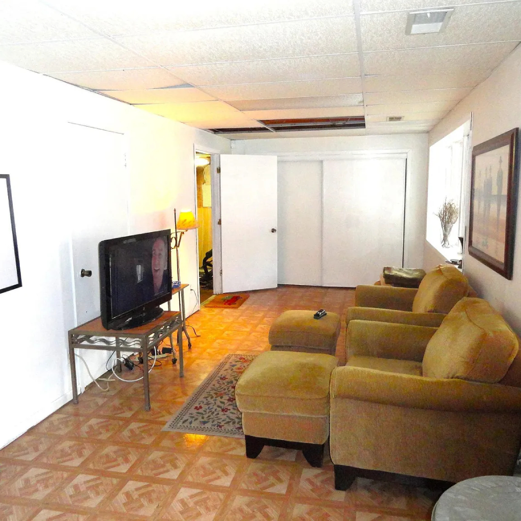 A cozy, well-lit living room with soft furniture and a fireplace, showing a television for basic cable access.
